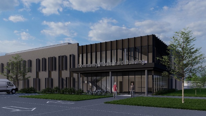 Modern Community Works Yard Building with large windows and two people walking near the entrance under a partly cloudy sky.